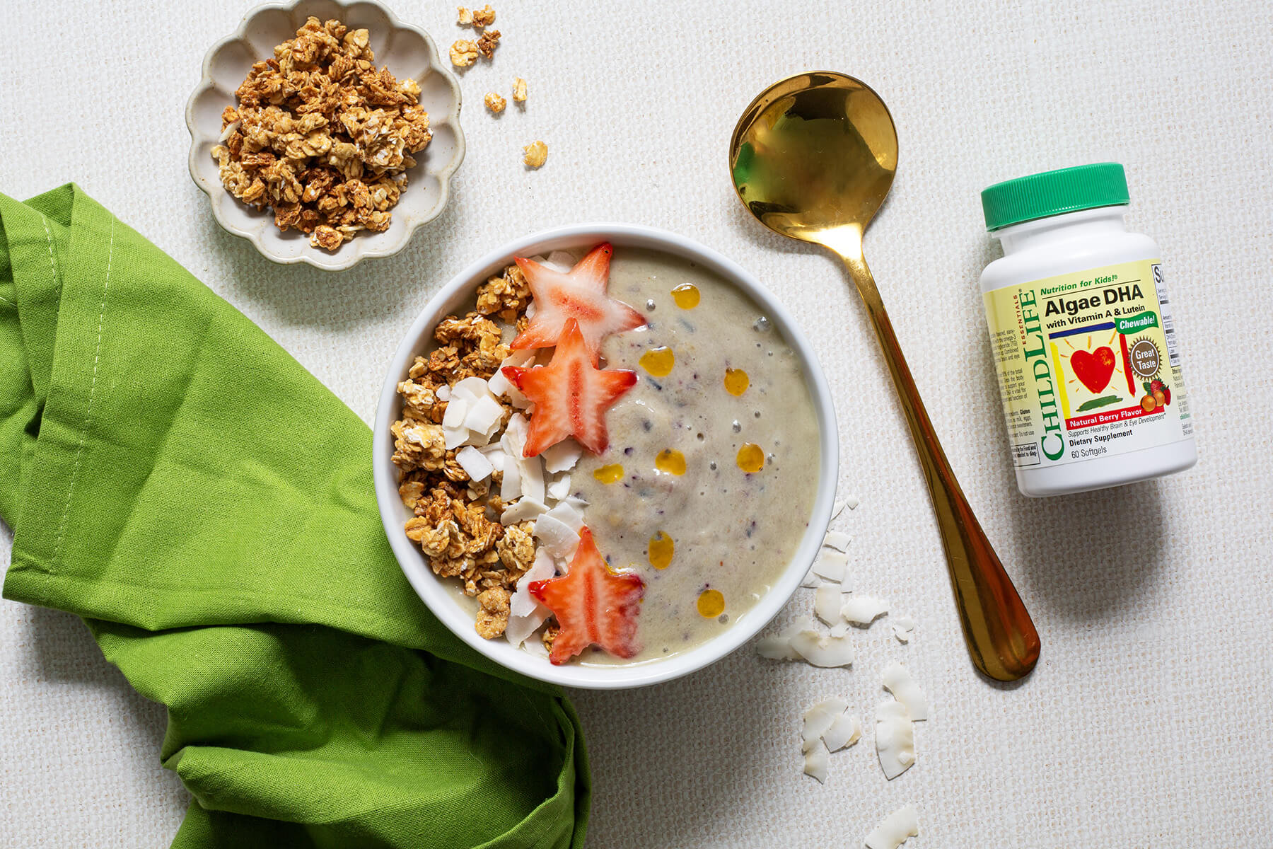 Thick tropical smoothie bowl topped with kiwi stars, coconut flakes, and granola arranged in a colorful mermaid tail pattern.
