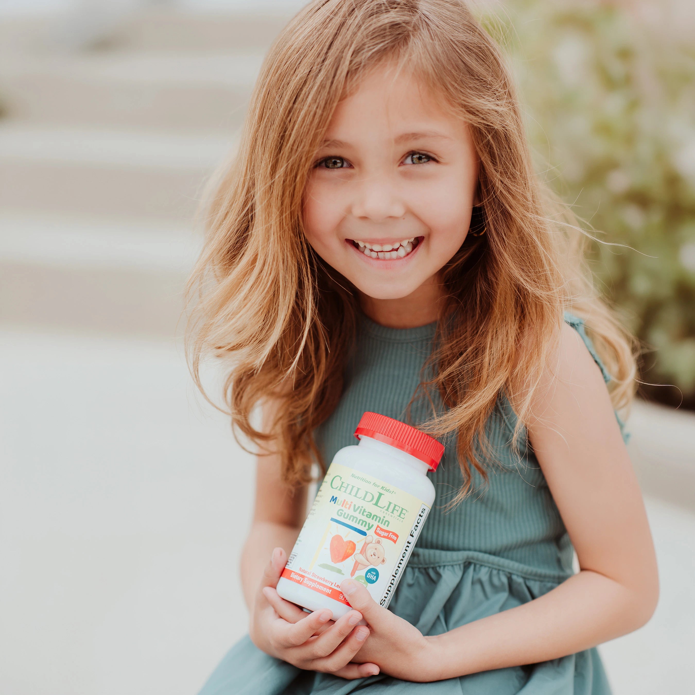Young girl holding a ChildLife MultiVitamin Gummy bottle