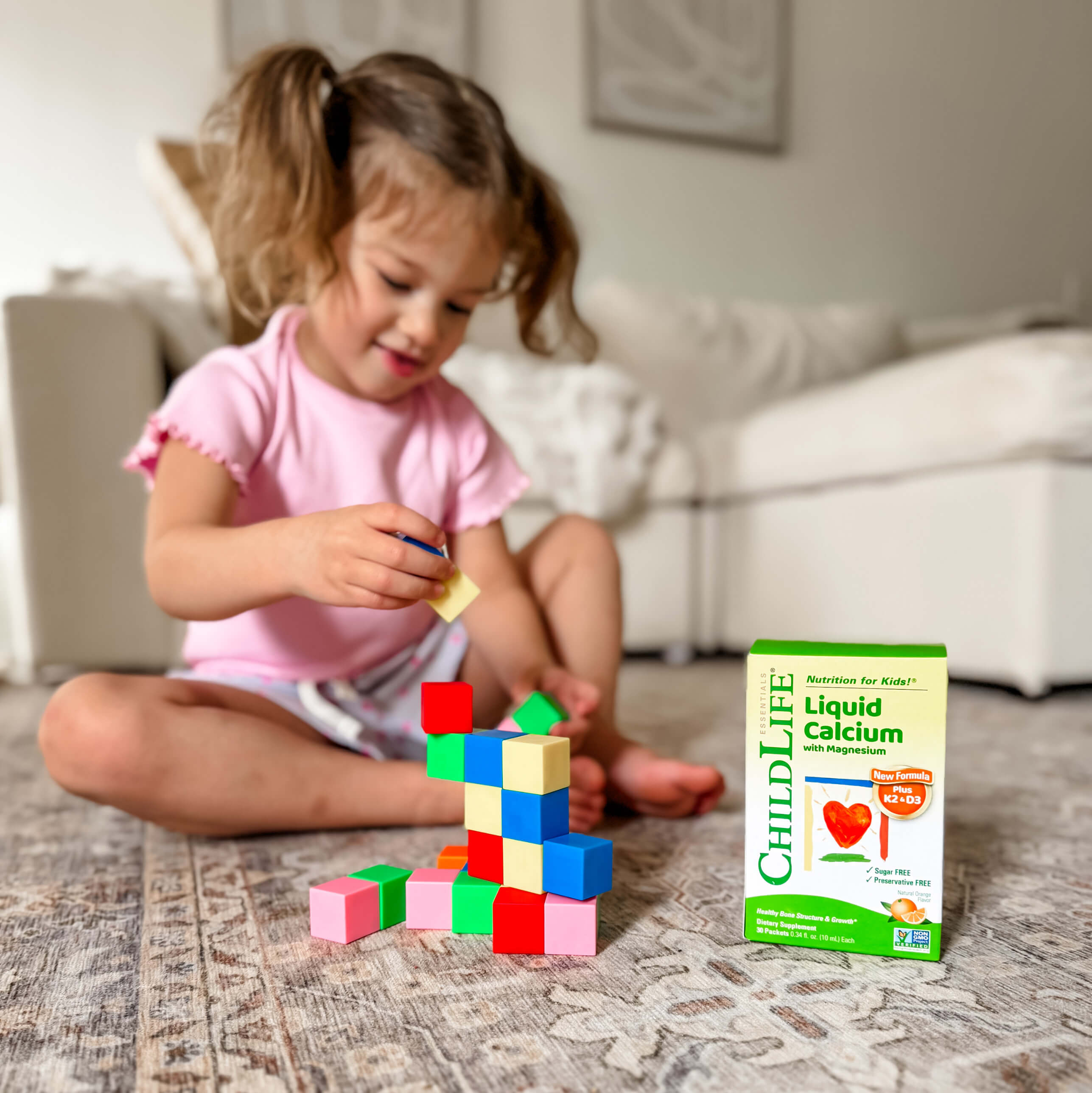 Child playing with colorful blocks next to a ChildLife Liquid Calcium with Magnesium box.